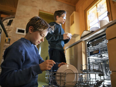 To drenge ved at fylde opvaskemaskinen en sen aften