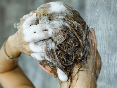 Kvinde vasker shampoo ud af håret