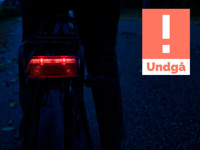 Cykel i mørke med baglygte der ikke lyser ret meget og et undgå logo