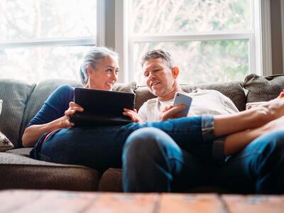 Midaldrende par i sofaen læser e-bøger