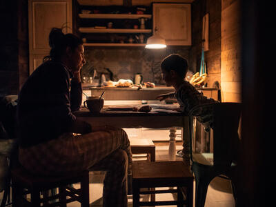 Mor og barn i køkkenet ved spisebordet i næsten mørke