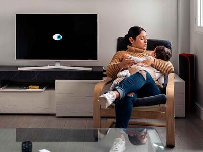 Kvinde med barn i lænestol ved siden af et smart-tv