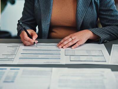 Aftaledokumenter på bord med tre menneskers hænder og arme