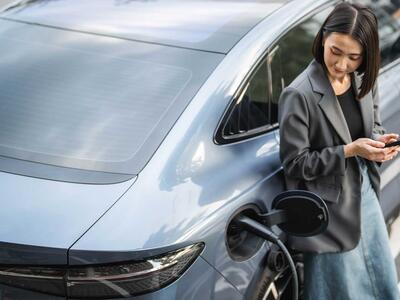 Kvinde står ved elbil, som er ved at blive opladet