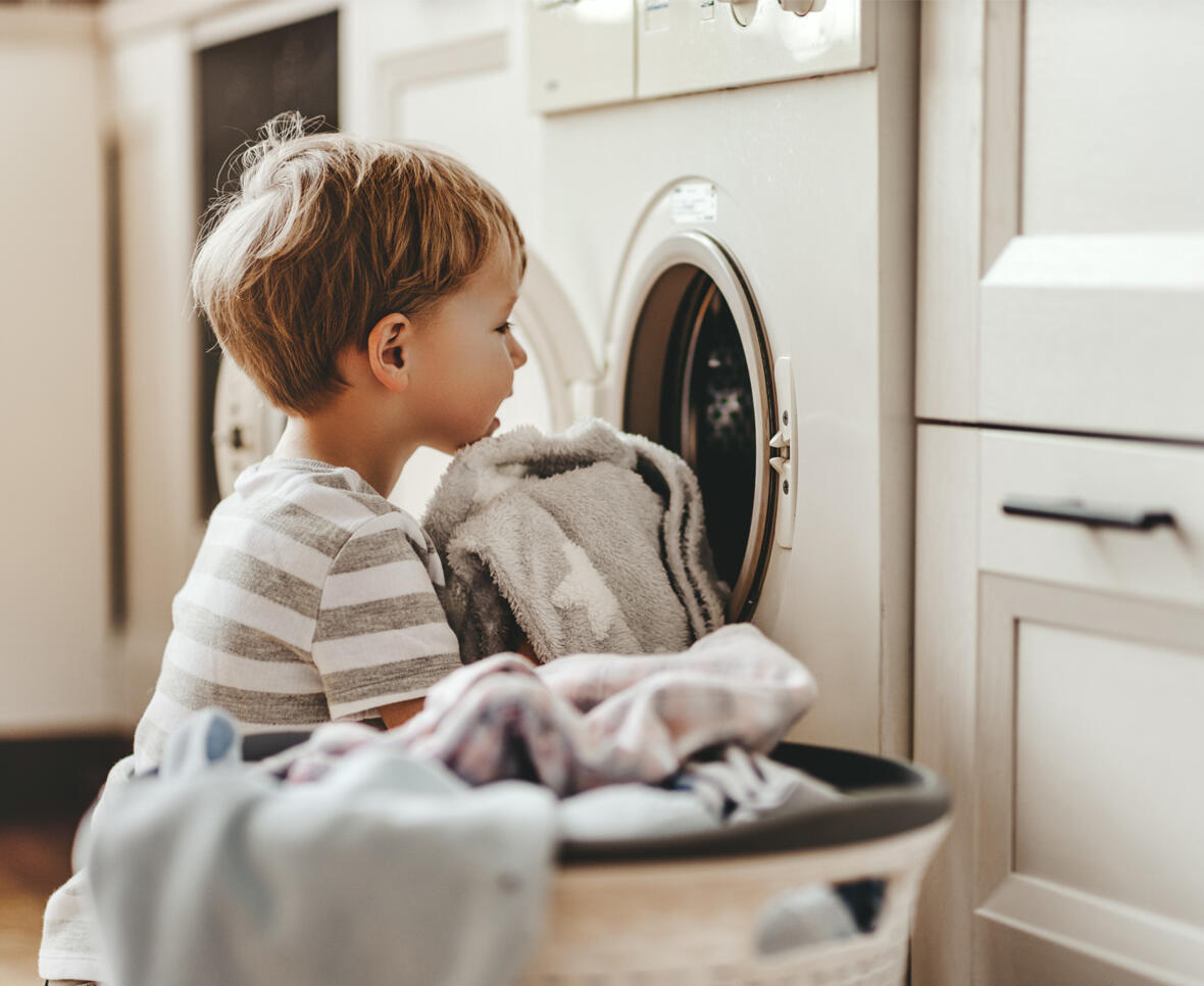 Barn ved vaskemaskine med vasketøj